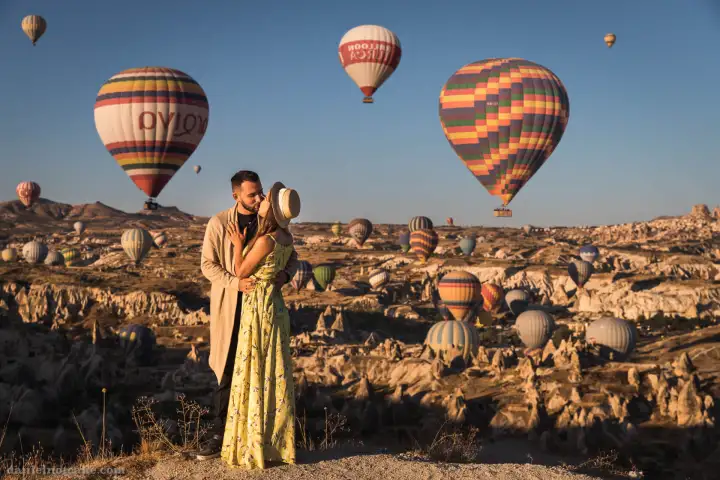 Romantic couple in valley watching hot air balloons