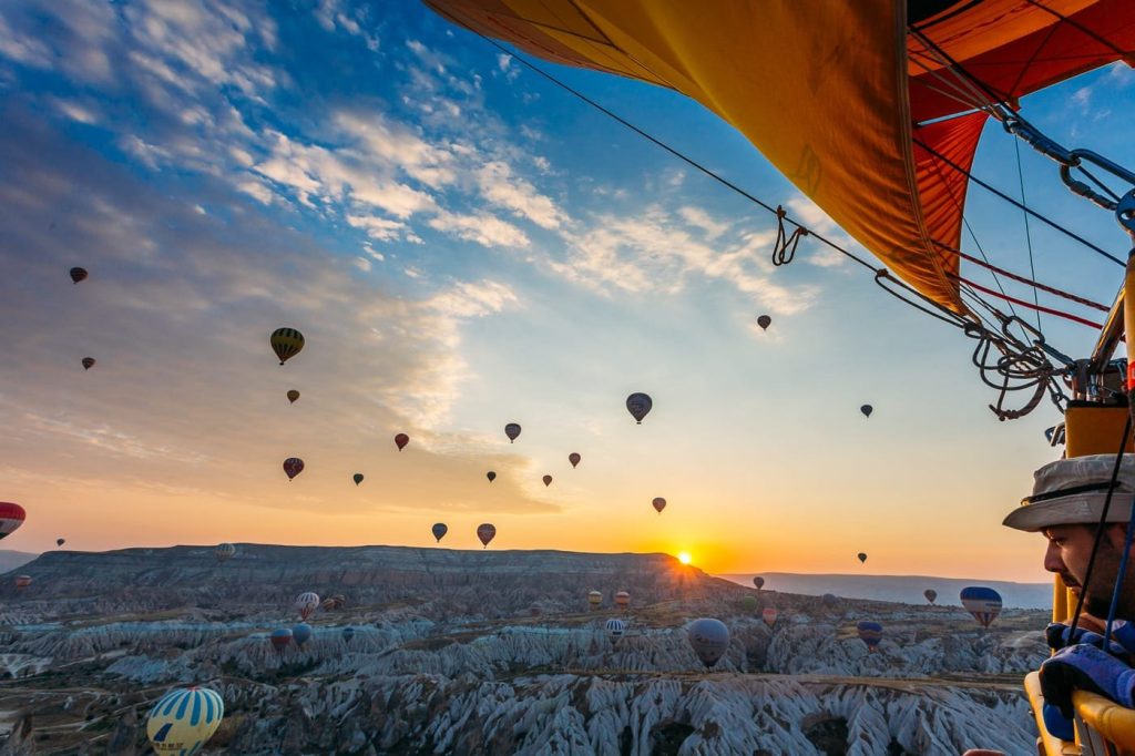 Stunning golden hour landscape in Cappadocia with hot air balloons in the sky.