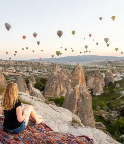 Picnic on cliff with sunrise view of hot air balloons