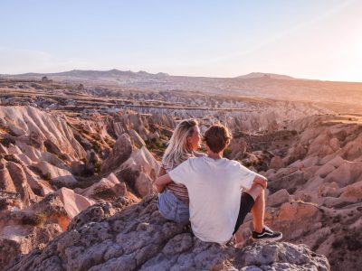 Couple on cliff edge at sunset overlooking valley