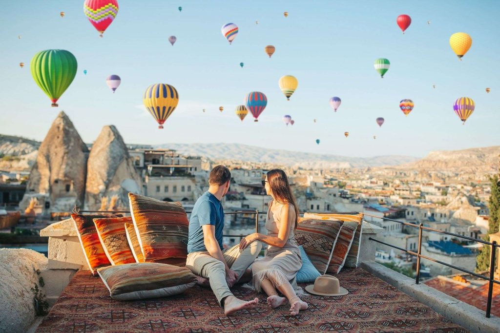 Couple relaxing on terrace at sunrise with balloons