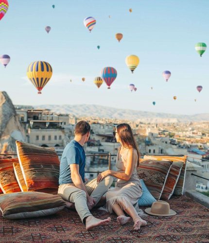 Couple relaxing on terrace at sunrise with balloons