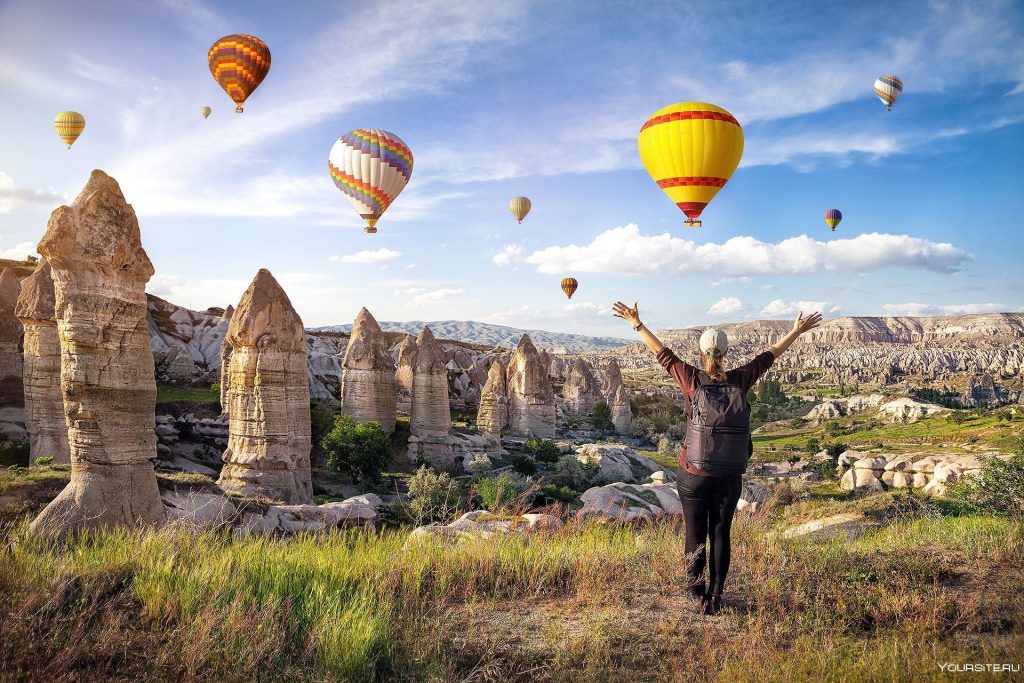 Colorful hot air balloons flying over the fairy chimneys of Cappadocia at sunrise