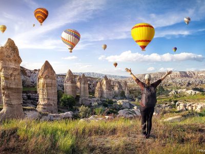 Man walking in fairy chimney landscape with balloons
