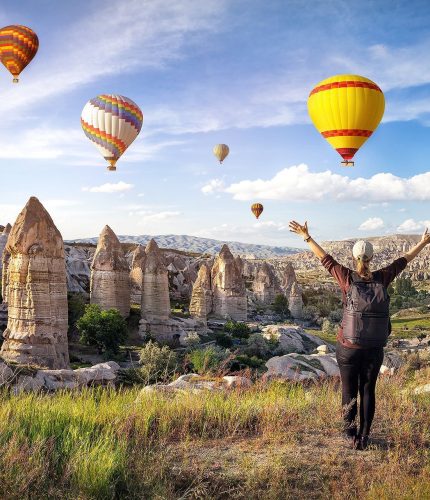 Man walking in fairy chimney landscape with balloons