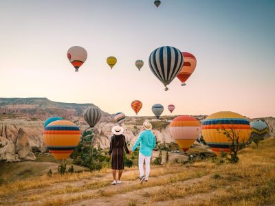 Family with child watching hot air balloons in field