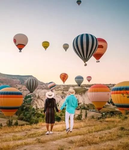Family with child watching hot air balloons in field