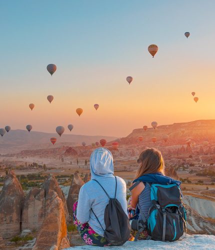 Travel couple at sunset viewpoint watching balloons