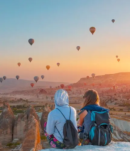 Travel couple at sunset viewpoint watching balloons