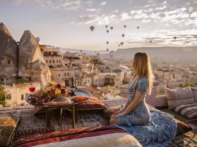 Woman enjoying breakfast on terrace overlooking balloons