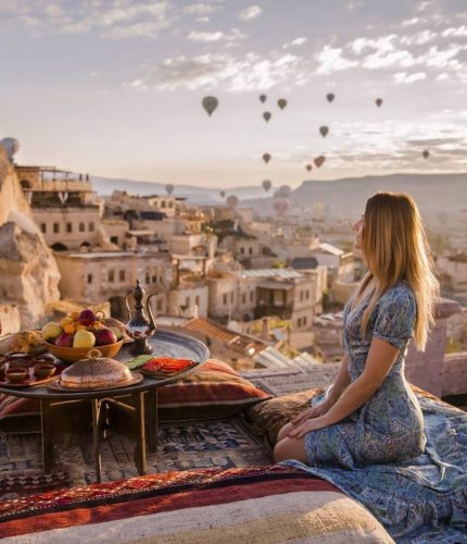 Woman enjoying breakfast on terrace overlooking balloons