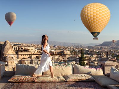 Woman posing on terrace with hot air balloons sunrise