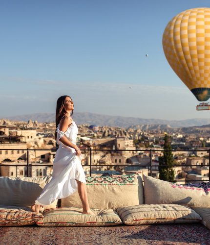 Woman posing on terrace with hot air balloons sunrise