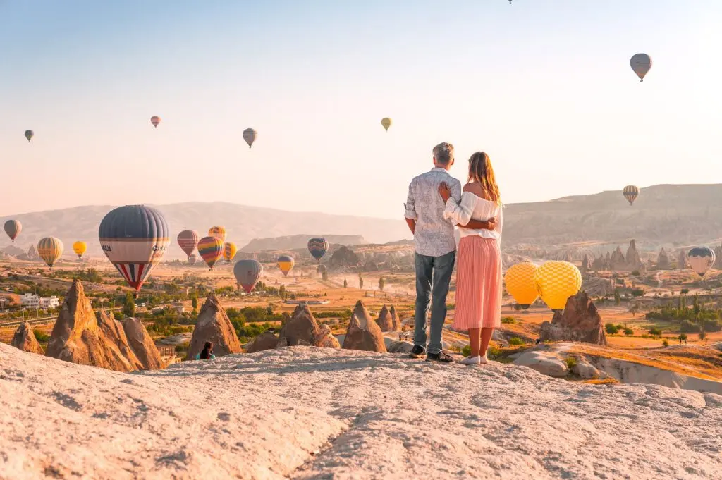 Wedding couple on hilltop at sunset with balloons