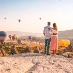 Wedding couple on hilltop at sunset with balloons
