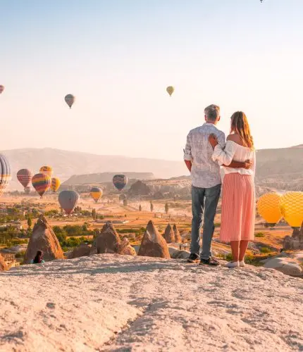 Wedding couple on hilltop at sunset with balloons