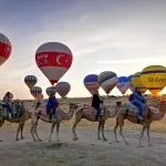 Camel trek in Cappadocia with hot air balloons in background