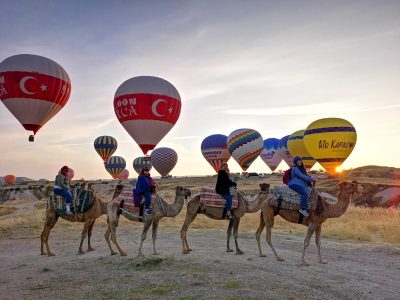 Camel trek in Cappadocia with hot air balloons in background