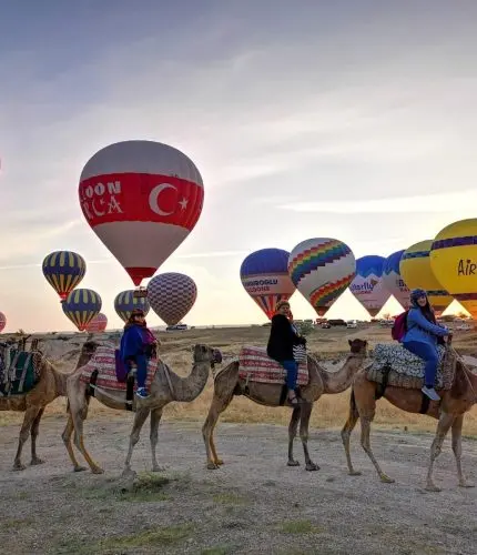 Camel trek in Cappadocia with hot air balloons in background