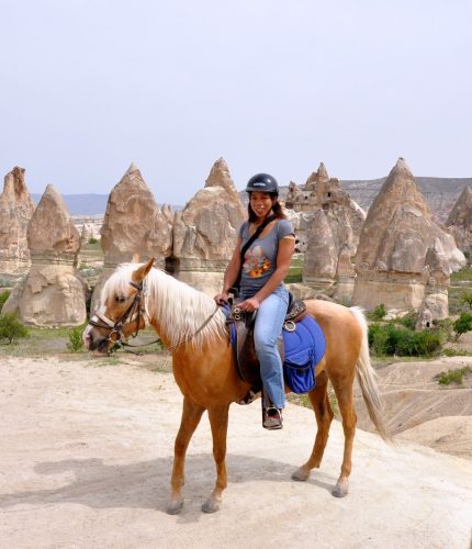Tourists riding horses near fairy chimneys in Cappadocia