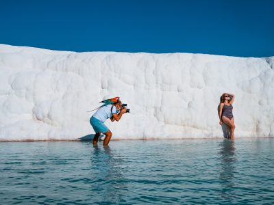 People swimming in thermal pool below Pamukkale white cliffs