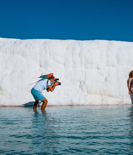 People swimming in thermal pool below Pamukkale white cliffs