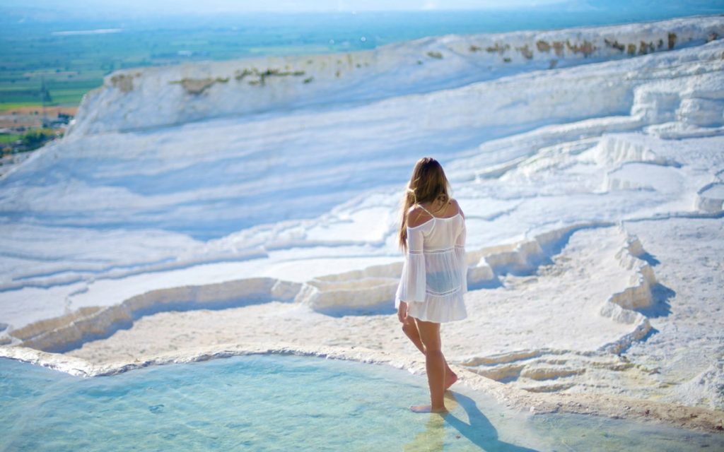 Woman walking on Pamukkale white terraces panorama